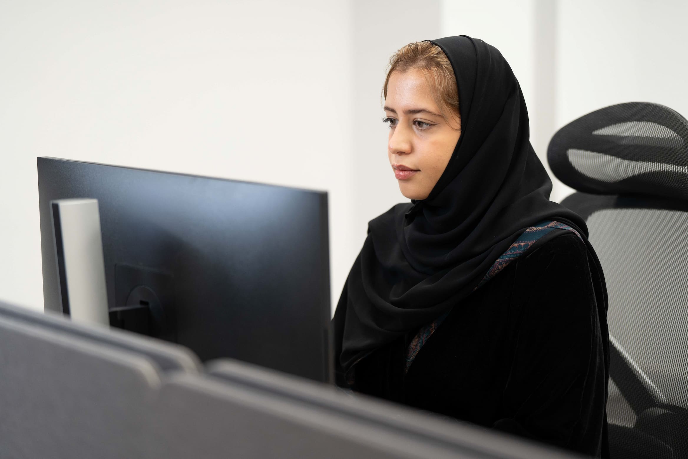 Employee dressed in hijab focused at computer