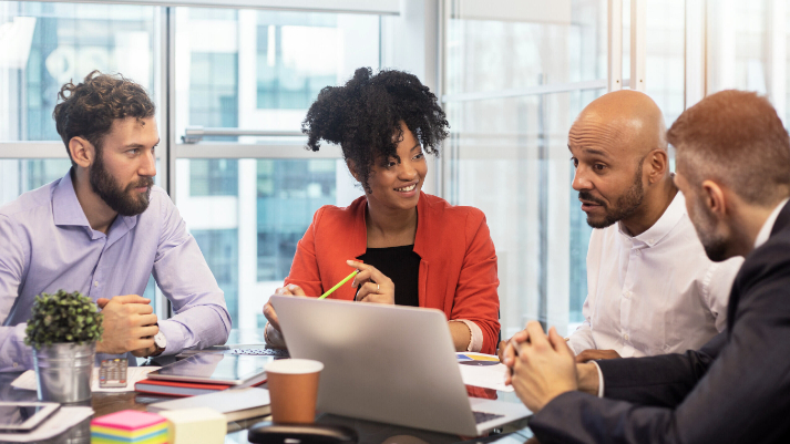 a group of BAE Systems senior engineers sit around a table having a meeting