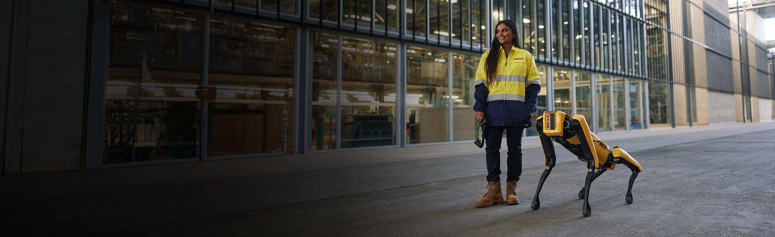 An employee at BAE Systems Australia stood next to a robotic dog