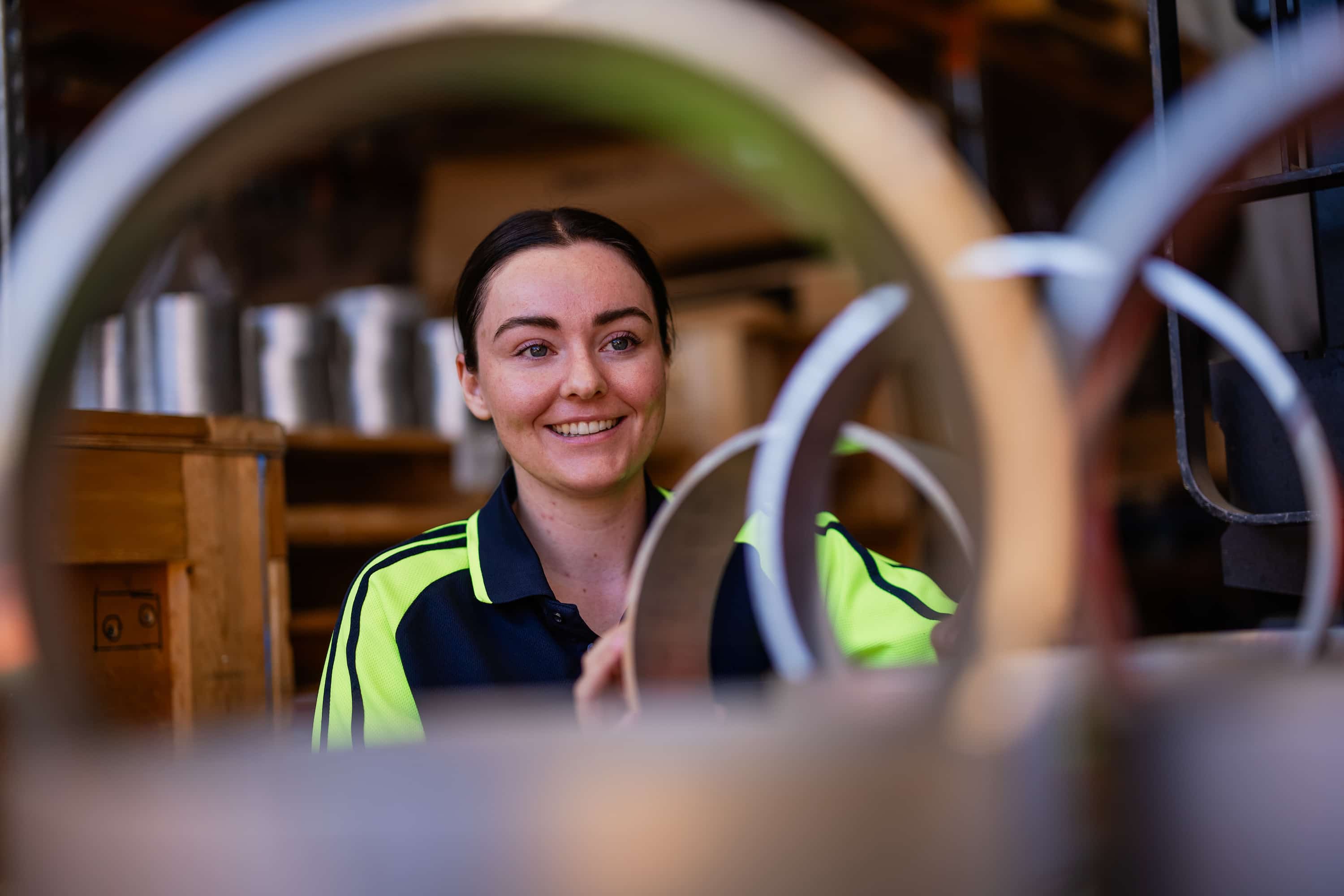 Woman smiling wearing high visbility gear through metal circles