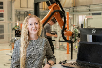 An apprentice at BAE Systems stands beside a computer screen