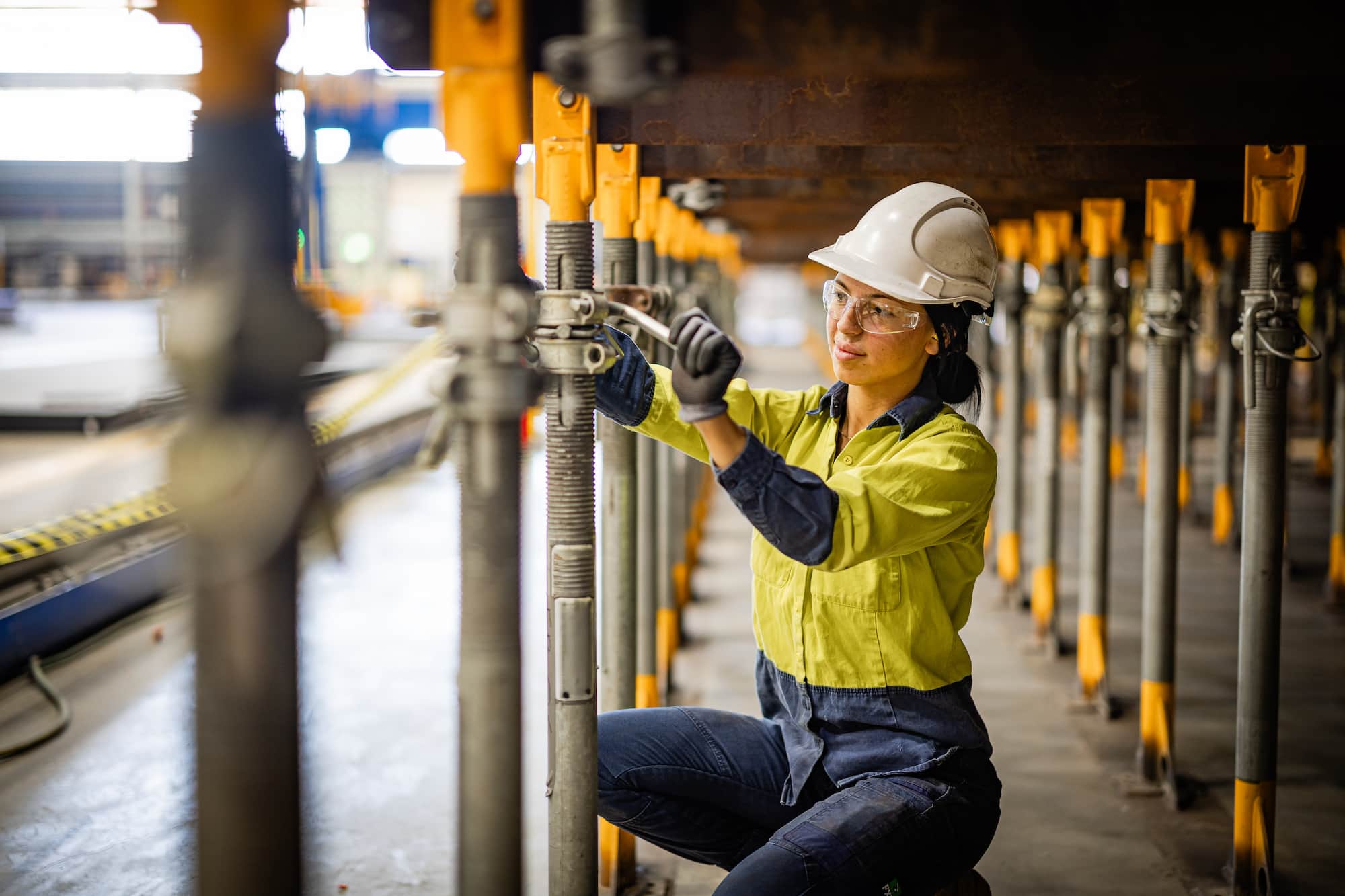 Female worker tightening scaffolding on workshop floor