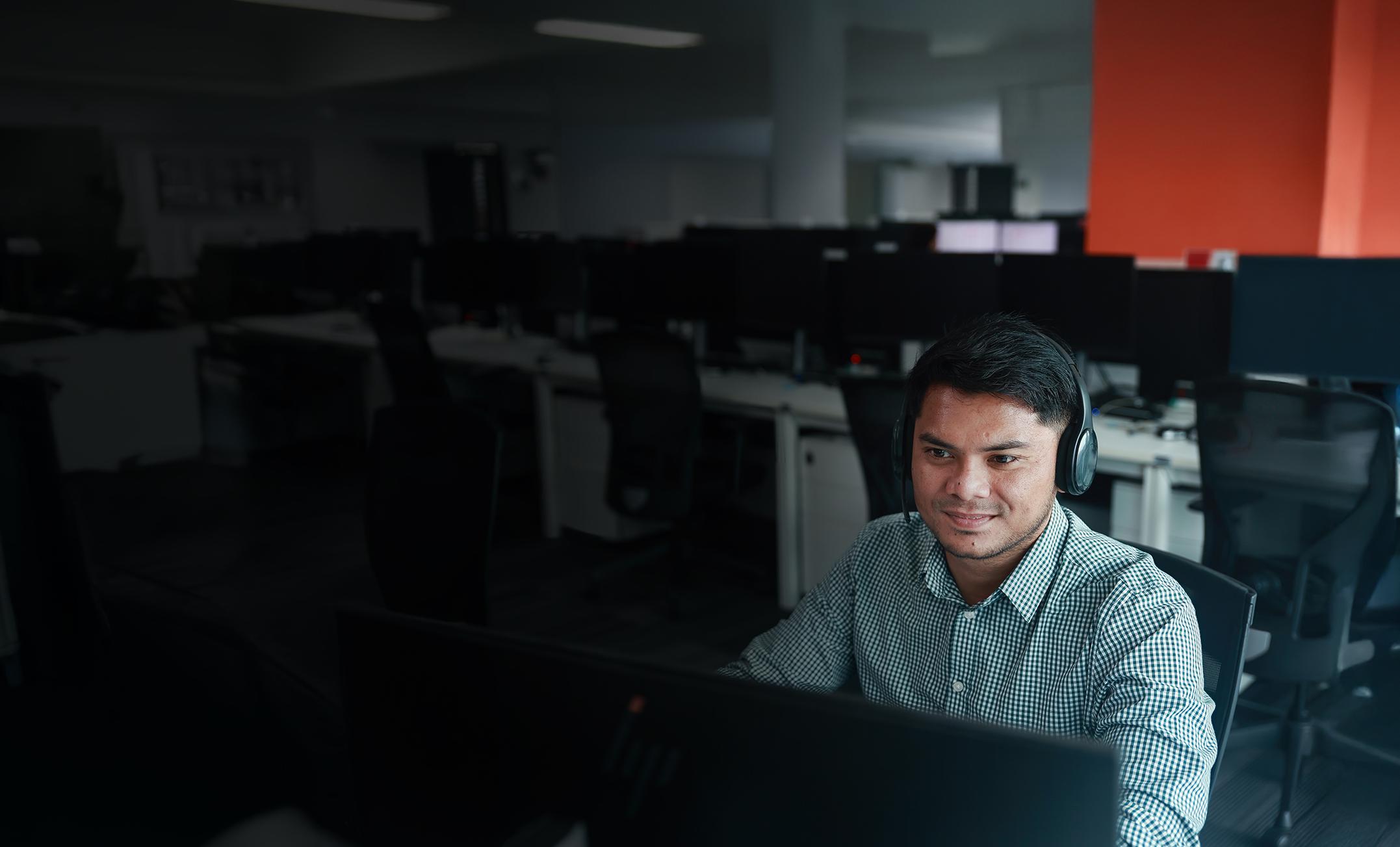 Man wearing a headset working at a computer in an office